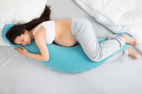 Nằm ngủ nghiêng về bên trái, sử dụng gối kê giữa hai đầu gối, dưới bụng và sau lưng để tạo điểm tựa, giúp cơ thể thả lỏng thoải mái
