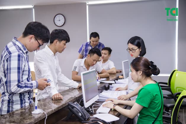 Nhân viên quầy lễ tân hướng dẫn người bệnh điền thông tin vào hồ sơ khám bệnh