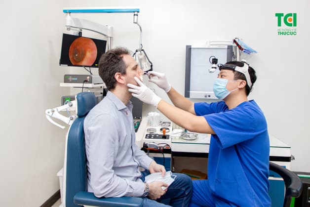Bác sĩ chuyên khoa Tai Mũi Họng, đang thực hiện quá trình khám tai-mũi-họng cho một bệnh nhân nước ngoài tại phòng khám ĐKQT Thu Cúc.