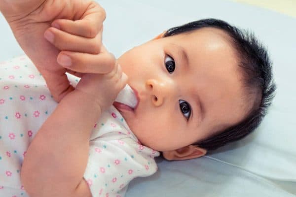 Nhúng gạc vào nước ấm và lau nhẹ nhàng nướu của bé sau khi ăn hoặc trong lúc tắm cho bé