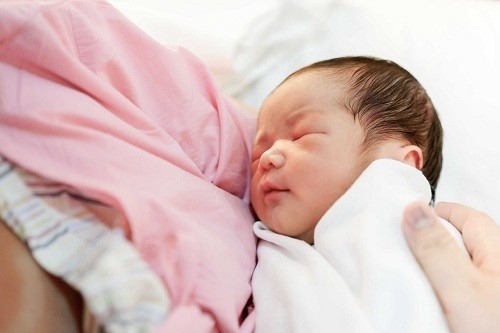 Nhanh chóng lau khô trẻ, bọc trẻ sơ sinh bằng vải mềm và đặt lên bụng mẹ, da kề da với mẹ.