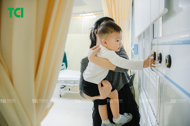 Mẹ bế trẻ sau khi cắt thắng lưỡi tại Thu Cúc TCI, trẻ sinh hoạt bình thường và không cần kiêng khem đặc biệt.