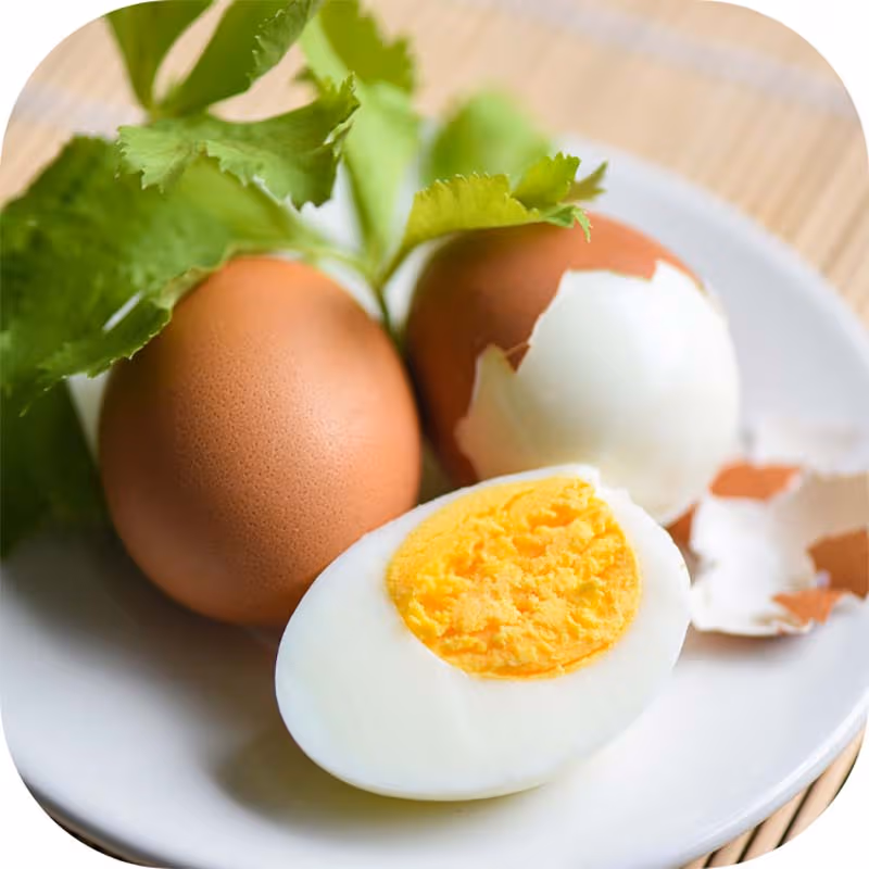 Đĩa trứng luộc đã bóc vỏ cùng trứng nguyên vỏ và rau trang trí, minh họa lượng calo trong một quả trứng luộc.