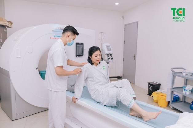 Kỹ thuật viên hướng dẫn người bệnh nằm lên bàn để chụp CT phổi