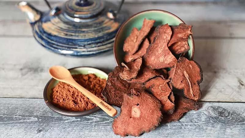 Hà thủ ô dạng lát khô và bột hà thủ ô đặt cạnh ấm trà.